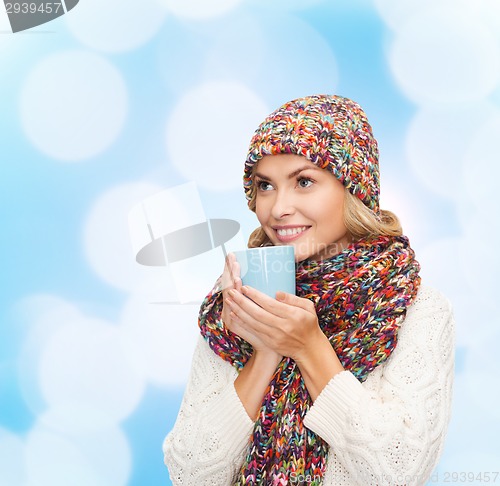 Image of smiling young woman in winter clothes with cup