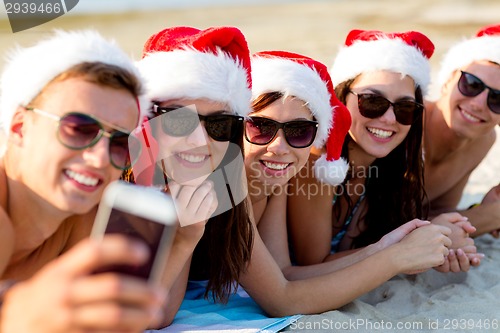 Image of group of friends in santa hats with smartphone