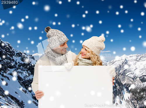 Image of smiling couple in winter clothes with white board