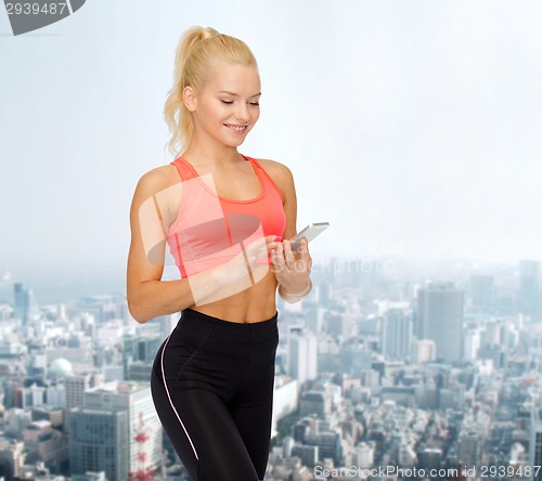 Image of smiling sporty woman with smartphone