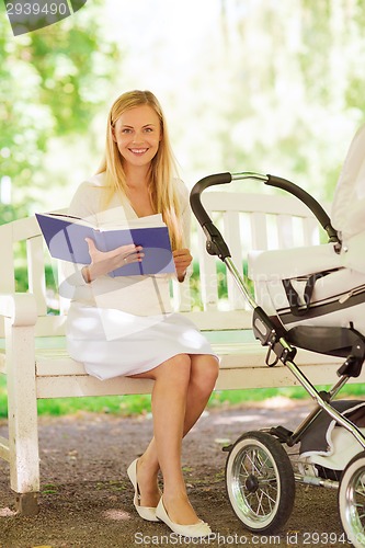 Image of happy mother with book and stroller in park