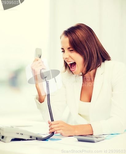 Image of woman shouting into phone in office