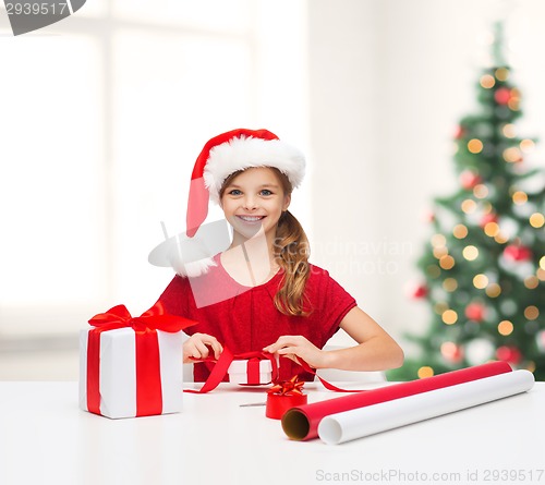 Image of smiling girl in santa helper hat with gift box