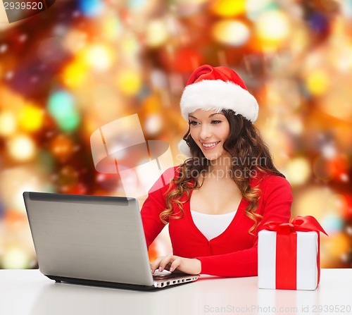 Image of smiling woman with gift box and laptop