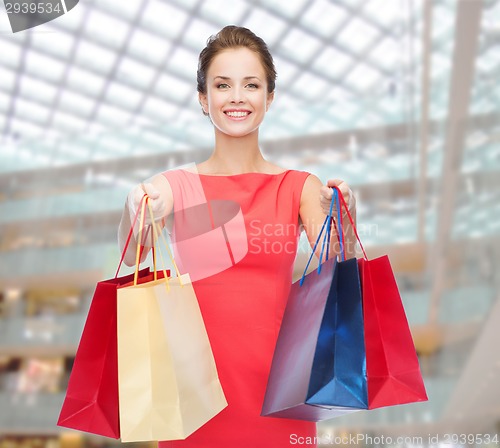 Image of smiling elegant woman in dress with shopping bags