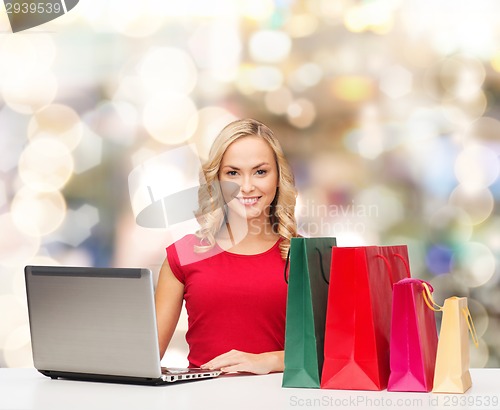 Image of smiling woman in red shirt with gifts and laptop