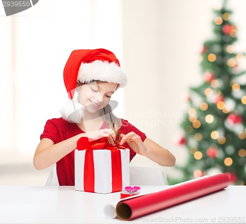 Image of smiling girl in santa helper hat with gift box