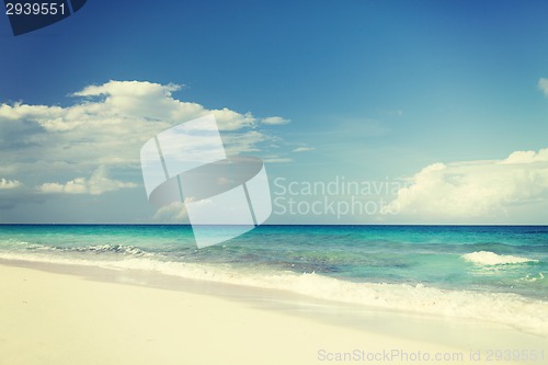 Image of blue sea or ocean, white sand and sky with clouds