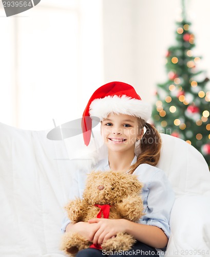 Image of smiling girl in santa helper hat with teddy bear