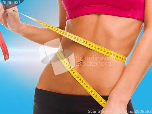 Image of close up of trained belly with measuring tape