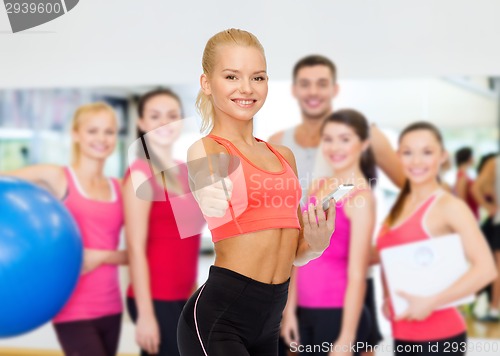 Image of smiling sporty woman with smartphone