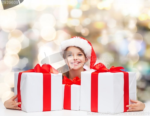 Image of smiling girl in santa helper hat with gift boxes