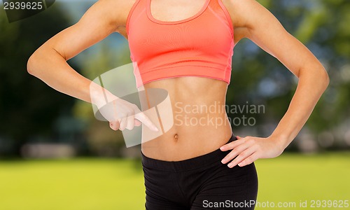 Image of close up of woman pointing finger at her six pack