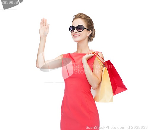 Image of smiling elegant woman in dress with shopping bags