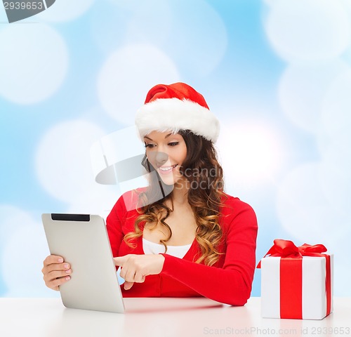 Image of smiling woman in santa hat with gift and tablet pc