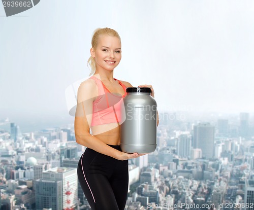 Image of smiling sporty woman with jar of protein