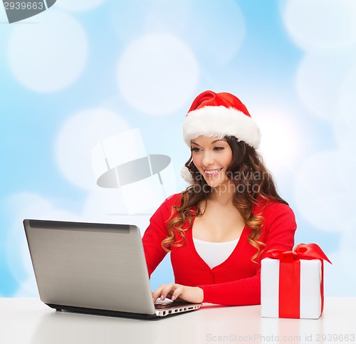 Image of smiling woman with gift box and laptop