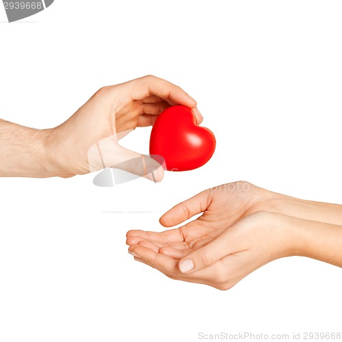 Image of man hand giving red heart to woman