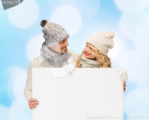 Image of smiling couple in winter clothes with white board