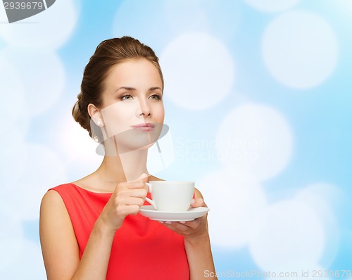 Image of smiling woman in red dress with cup of coffee