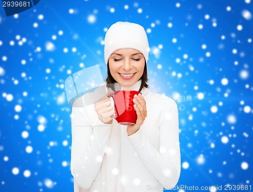 Image of smiling young woman in winter clothes with cup