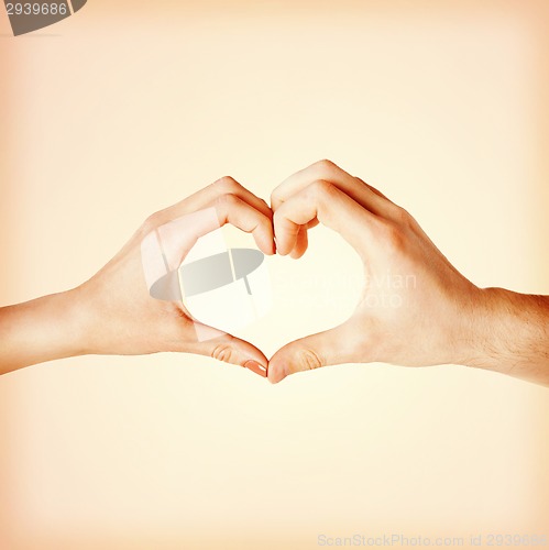 Image of woman and man hands showing heart shape