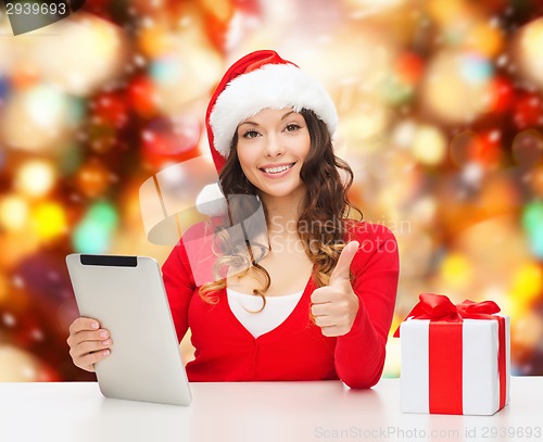 Image of smiling woman in santa hat with gift and tablet pc