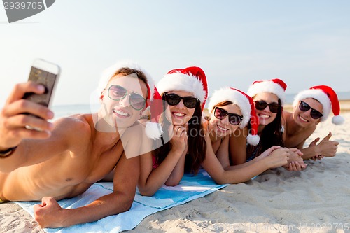 Image of group of friends in santa hats with smartphone