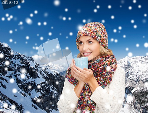 Image of smiling young woman in winter clothes with cup