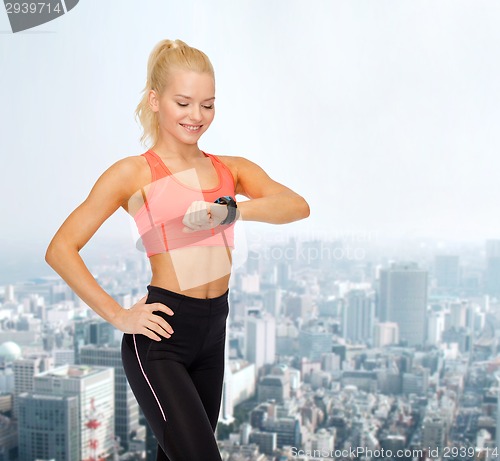 Image of smiling woman with heart rate monitor on hand