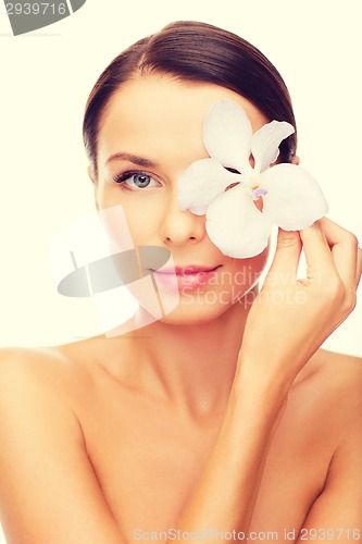 Image of relaxed woman with orchid flower over eye