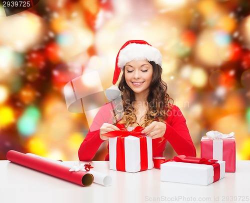 Image of smiling woman in santa helper hat packing gifts