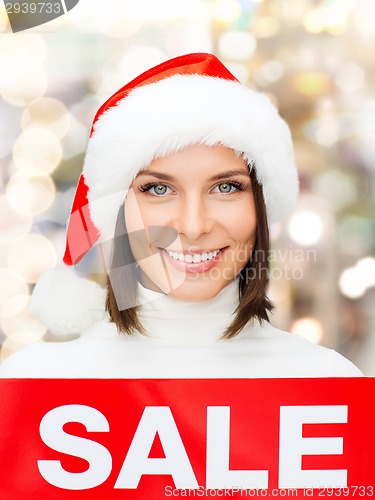 Image of smiling woman in santa helper hat with sale sign