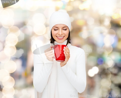 Image of smiling young woman in winter clothes with cup