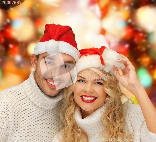 Image of smiling couple in sweaters and santa helper hats