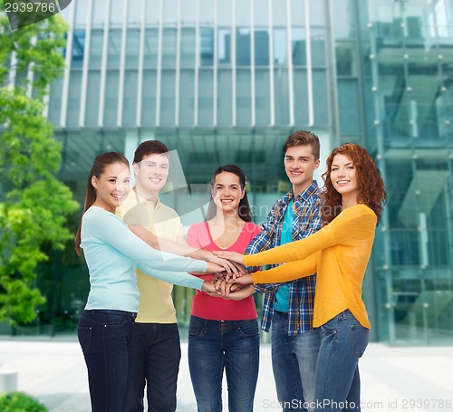 Image of smiling teenagers with hands on top of each other