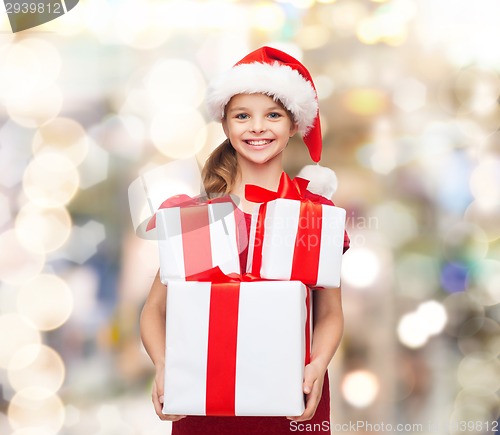 Image of smiling little girl in santa helper hat with gifts