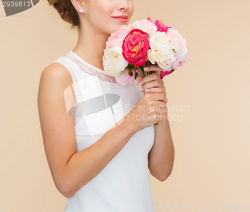 Image of smiling woman in white dress with bouquet of roses