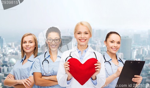 Image of smiling female doctor and nurses with red heart