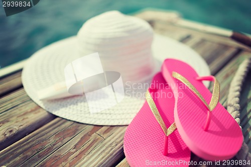 Image of close up of hat, sunscreen and slippers at seaside