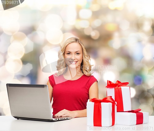 Image of smiling woman in red shirt with gifts and laptop