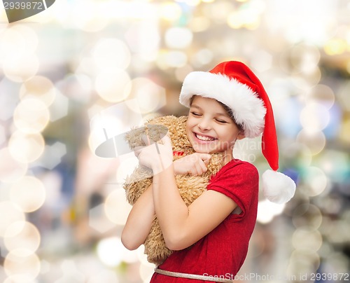 Image of smiling girl in santa helper hat with teddy bear