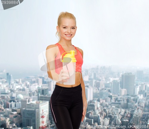 Image of smiling sporty woman with protein shake bottle