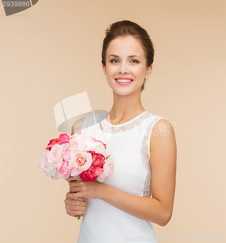 Image of smiling woman in white dress with bouquet of roses
