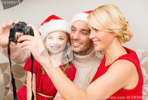 Image of smiling family in santa helper hats taking picture
