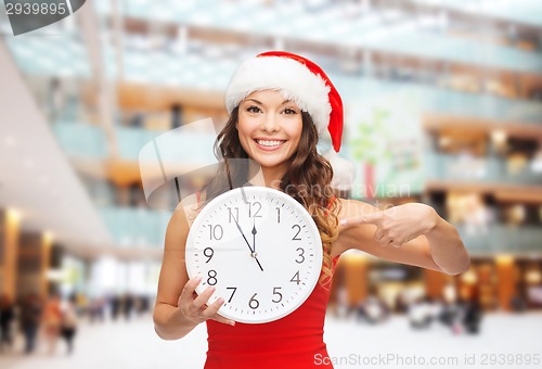 Image of smiling woman in santa helper hat with clock