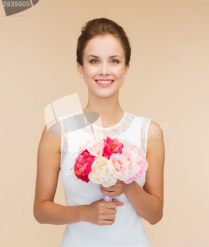 Image of smiling woman in white dress with bouquet of roses