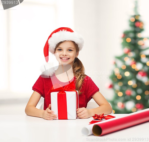 Image of smiling girl in santa helper hat with gift box