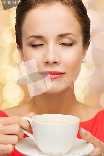 Image of smiling woman in red dress with cup of coffee