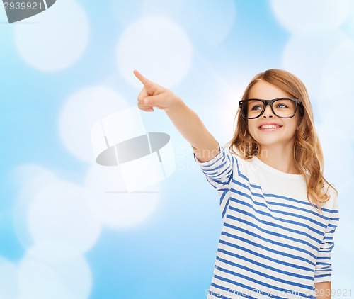 Image of cute little girl in eyeglasses pointing in the air